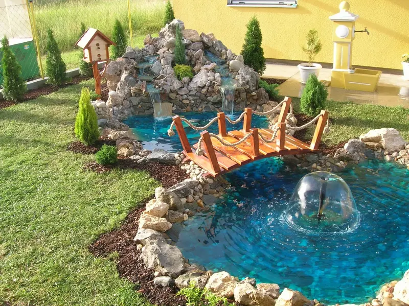 Fontana u bazenu sa drvenim mostićem i kamenim vodopadom
